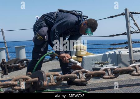 170630-N-ZE250-003 MER MÉDITERRANÉE (30 juin 2017) - Maître de Manœuvre Seaman Apprentice Tariq Doolin procède à la préservation l'entretien sur la chaîne d'ancre à bord de la classe Arleigh Burke destroyer lance-missiles USS Carney (DDG 64) dans la mer Méditerranée le 30 juin 2017. Carney, l'avant-déployé à Rota, Espagne, effectue actuellement sa troisième patrouille dans la sixième flotte américaine zone d'opérations à l'appui de la sécurité nationale des États-Unis en Europe. (U.S. Photo par marine Spécialiste de la communication de masse de la classe 3ème Weston Jones/libérés) Banque D'Images