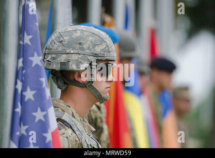 Les soldats de l'Arménie, Croatie, Monténégro, Roumanie, Ukraine et Etats-Unis attendre d'élever leur drapeau du pays au cours de la cérémonie d'ouverture officielle de l'exercice multinational Getica 17 Sabre au Centre national de formation conjointe à Cincu, la Roumanie, le 7 juillet 2017. Getica est un sabre 17 U.S-led l'appui feu exercice de coordination interarmes et d'exercice de tir réel qui intègre six pays alliés et les pays partenaires avec plus de 4 000 soldats. Getica Sabre fonctionne simultanément avec gardien, un sabre de l'armée américaine dirigée par l'Europe, un exercice multinational qui s'étend à travers la Bulgarie, la Hongrie et la Roumanie wi Banque D'Images