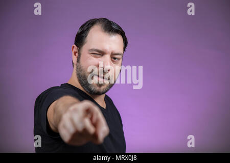 Un homme adulte est de pointer du doigt vous/ quelqu'un, sur fond mauve Banque D'Images