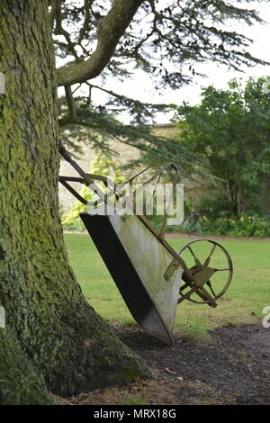 Brouette victorien antique appuyé contre un CedarTree, Canons Ashby, Northamptonshire Banque D'Images