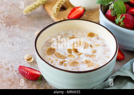 Petit-déjeuner sain close-up - flocons de céréales entières, de lait et de fraises fraîches sur fond d'ardoise ou de pierre. Le concept de nutrition santé. Banque D'Images