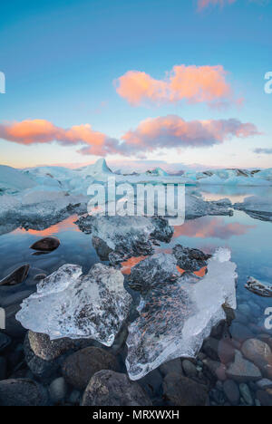 L'Est, l'Islande, l'Islande, le nord de l'Europe. L'emblématique peu icebergs dans la lagune bordée de glaciers au cours d'un lever du soleil Banque D'Images