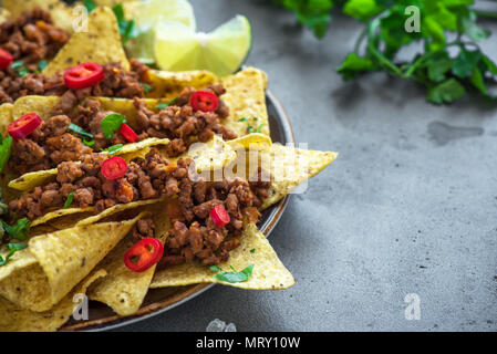 Nacho chips tortilla Maïs mexicain avec le fromage, la viande, le guacamole et red hot salsa épicée. Nachos avec du boeuf haché sur fond sombre, copie espace rustique. Banque D'Images