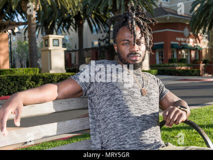 Handsome young African American man assis sur le banc dans le parc. Banque D'Images