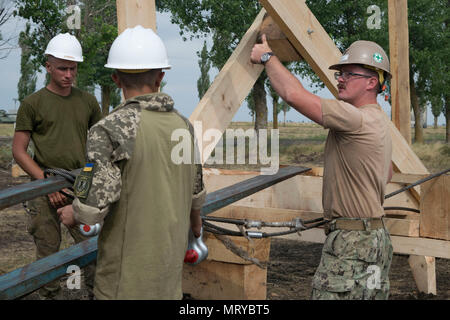 170713-N-DD899-009 SHIROKY LAN, l'Ukraine (13 juillet 2017) 3ème classe constructeur Robert Stewart, droite, signaux pour soulever la structure d'un tour de garde en cours de construction au cours de l'exercice Sea Breeze 2017 Shiroky à base d'entraînement de Lan le 13 juillet. Brise de Mer est une aux États-Unis et l'Ukraine co-organisé l'exercice maritime multinational qui s'est tenue à la mer Noire et est conçu pour améliorer l'interopérabilité des pays participants et de renforcer la sécurité maritime dans la région. (U.S. Photo par marine Spécialiste de la communication de masse 1re classe Sharay Bennett/libérés) Banque D'Images