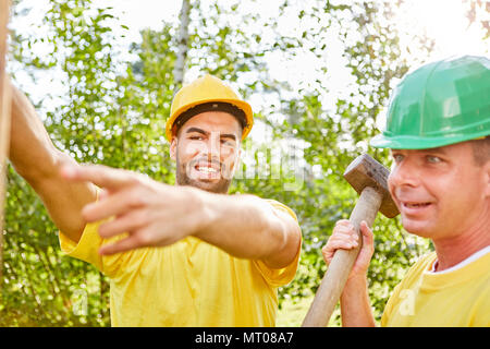 Deux travailleurs de la construction travaillent en équipe sur un chantier de construction pendant la construction d'une maison Banque D'Images