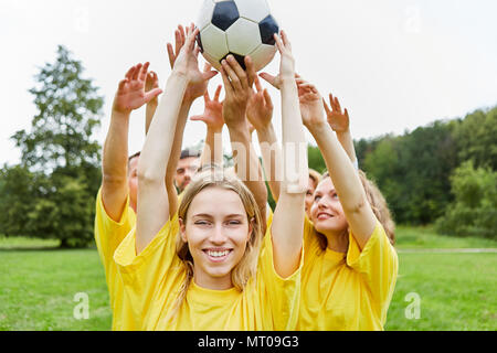 Jeune femme et son équipe font équipe avec le football formation Banque D'Images