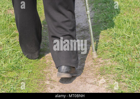 Homme avec bâton de marche portant des chaussures de marche sur Vieux rayé une route en terre (vue arrière) Banque D'Images