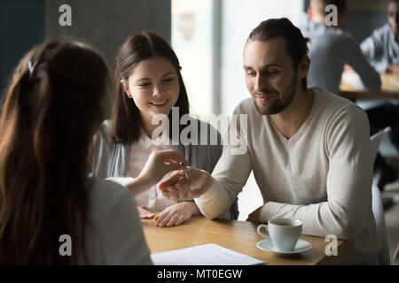 Heureux couple millénaire obtenir les clés de maison neuve d'agent immobilier Banque D'Images