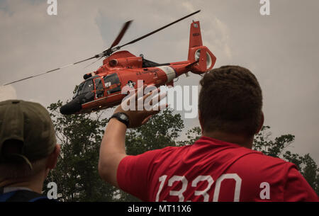 Andrew Reed, une troupe de scouts de la vie 1330 à New Jersey observe son père, le lieutenant de la Garde côtière canadienne le Cmdr. Jamie Reed, un pilote d'Air Station Atlantic City et eagle scout, piloter un hélicoptère MH-65 Dolphin au cours d'une démonstration de survie en eau. Plus de 30 000 scouts, chefs de troupes, les bénévoles et les membres du personnel professionnel, ainsi que plus de 15 000 visiteurs sont attendus à la 2017 Jamboree National. Environ 1 400 militaires du ministère de la Défense nationale et la garde côtière des États-Unis sont de fournir un soutien logistique pour l'événement. (U.S. Photo de l'armée par le Sgt. Jazmin Jenkins/22e Mob Banque D'Images