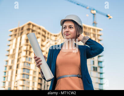 Belle femme d'affaires ingénieur est debout avec plan de papiers. Banque D'Images