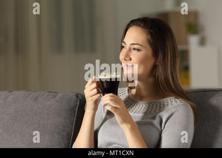 Satisfait woman enjoying coffee dans la nuit, assis sur un canapé dans la salle de séjour à la maison Banque D'Images