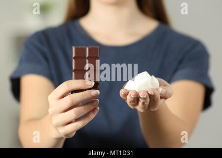 Vue avant close up of a woman mains montrant le sucre et le chocolat assis sur un canapé dans la salle de séjour à la maison Banque D'Images