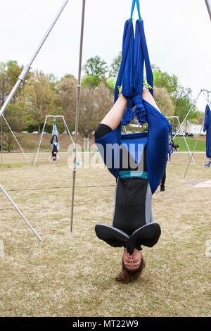 Une femme est suspendu à l'envers à l'aide de tissu attaché à des poteaux, alors qu'elle prend part à une classe de yoga dans la région de Piedmont Park à Atlanta, GA, le 8 avril 2018. Banque D'Images