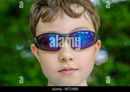 Un portrait d'un jeune garçon portant des lunettes de soleil. Banque D'Images