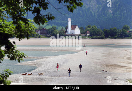 27 mai 2018, l'Allemagne, Schwangau : personnes marchant dans la baisin du lac Forggensee à sec avec l'église de Waltenhofen dans l'arrière-plan. Le plus grand réservoir peuvent actuellement pas être endigué, en raison de travaux de maintenance sur le barrage. Photo : Karl-Josef Opim/dpa Banque D'Images