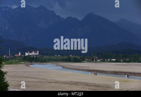 27 mai 2018, l'Allemagne, Schwangau : personnes marchant dans la baisin du lac Forggensee à sec avec palace à Füssen en arrière-plan. Le plus grand réservoir peuvent actuellement pas être endigué, en raison de travaux de maintenance sur le barrage. Photo : Karl-Josef Opim/dpa Banque D'Images