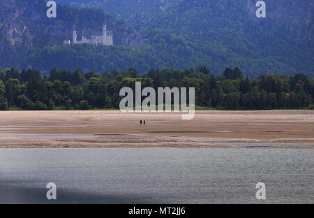 27 mai 2018, l'Allemagne, Schwangau : personnes marchant dans la baisin du lac Forggensee à sec avec le château de Neuschwanstein en arrière-plan. Le plus grand réservoir peuvent actuellement pas être endigué, en raison de travaux de maintenance sur le barrage. Photo : Karl-Josef Opim/dpa Banque D'Images