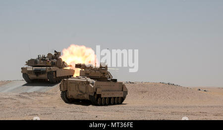 Un M1A2 Abrams char de combat principal engage l'équipage tout en fournissant des cibles de tir d'appui direct pour un élément de reconnaissance au cours de la formation à l'Hunter-Killer Koweït Multipurpose Éventail complexe 7 juin. L'Escadron sabre développe Hunter-Killer comme concept, la collaboration avec les réservoirs de Bradleys both a augmenté la puissance de feu et la vitesse dans la mission de reconnaissance. (U.S. Photo de l'armée par le sergent. Leah R. Kilpatrick/libérés) Banque D'Images