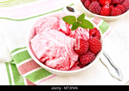 La crème glacée à la framboise rouge et menthe baies en blanc bol, une cuillère sur serviette sur planche de bois contexte Banque D'Images