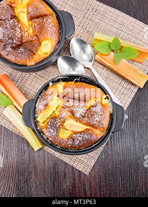 Clafouti à la rhubarbe tarte à la rhubarbe et menthe brazier, tiges sur serviette sur fond de planche de bois d'en haut Banque D'Images