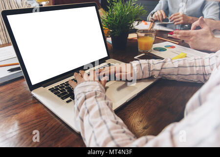 Des collègues de travail. Jeune femme travaillant de concert avec des collègues et en tapant un texte sur laptop in office loft. Concept d'équipe. Ordinateur portable écran blanc Banque D'Images