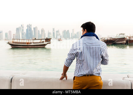 Vue arrière de l'extérieur de l'homme jeune Indien à la recherche au niveau de la vue de paysage urbain et de bateaux en bois traditionnels à corniche Banque D'Images