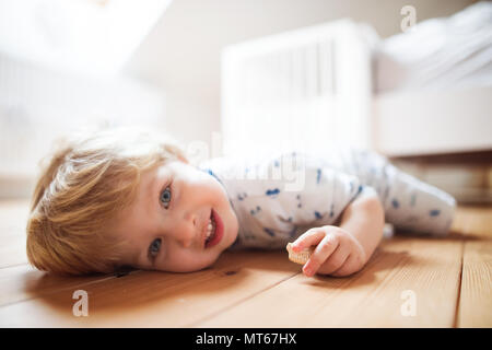 Un bébé garçon sur le plancher dans la chambre à coucher à la maison. Banque D'Images