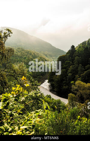 La lumière du soleil du matin tombe sur la paisible rivière Garry entouré de forêts alors que la brume enveloppe Ben Vrackie et Tenandry Hill au col de Killicrankie Banque D'Images