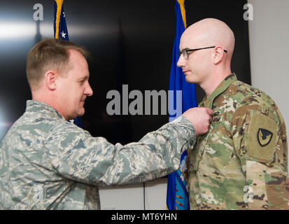 Le colonel Daniel Knight, gauche, 673d, commandant du Groupe de soutien à la Mission de l'Armée de l'air les broches médaille pour le s de l'armée. Mark Fitzgerald au cours de cérémonie à Joint Base Elmendorf-Richardson, Alaska, le 31 mars 2017. Bien qu'affecté à la 673e Escadron d'Fitzgerald exécuté huit contrats d'une valeur de 389 000 $ Appui à plus de 1 500 400 joint warfighter et intervenants de l'Agence fédérale de gestion des urgences pour faire de l'exercice 2014 de l'écran de l'Alaska. (U.S. Photo de l'Armée de l'air par le sergent. Sheila deVera) Banque D'Images