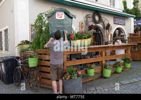 Un serveur au restaurant le Zirkelwirt à Salzbourg, Autriche posts le menu du jour promotions sur une ardoise à l'extérieur du restaurant. Banque D'Images