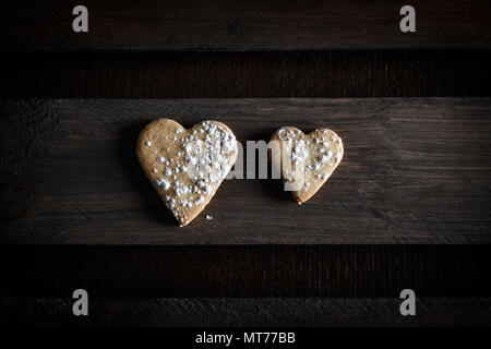 Deux délicieux cookies en forme de cœur saupoudrée de sucre glace dans une planche de bois. Image horizontale vue d'en haut. Concept d'amour en couple Banque D'Images