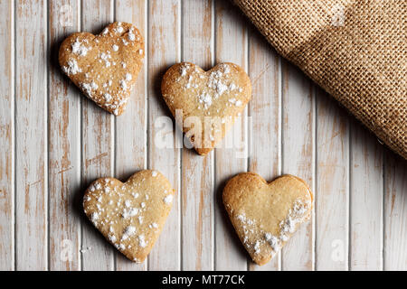 Délicieux cookies en forme de cœur saupoudrée de sucre glace dans une planche de bois. Image horizontale vue d'en haut. Banque D'Images