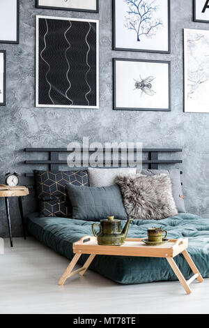 Électrique sur plateau en bois à côté d'un matelas vert dans la chambre intérieur avec des affiches sur les murs de béton Banque D'Images