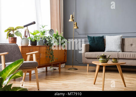 Table en bois à l'intérieur salon vintage avec le cabinet entre canapé et fauteuil. Photo réelle Banque D'Images