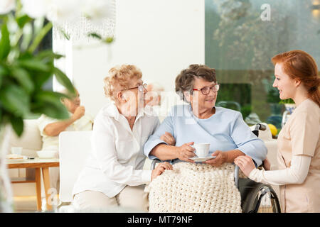 Parler à un soignant smiling senior femme et son ami dans la maison de soins infirmiers Banque D'Images