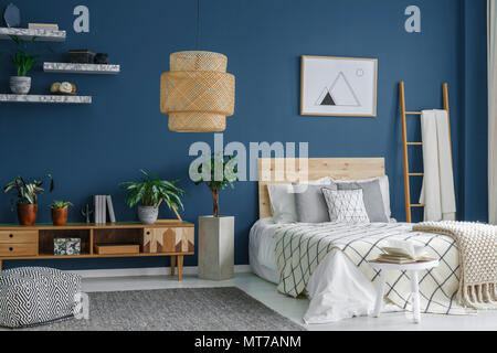 Vue latérale d'une chambre bleue intérieur avec une lampe moderne, d'un lit double, des plantes et du cabinet Banque D'Images