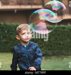 Magnifique petit garçon soufflant en gros des bulles de savon à l'automne.enfance heureux concept. Banque D'Images