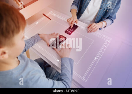 Deux personnes assises à la table et les smartphones touching futuristic Banque D'Images