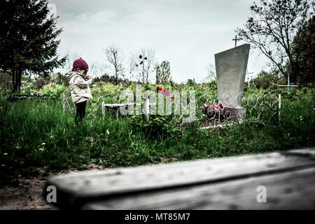 Une petite fille près de tombe dans le cimetière Banque D'Images