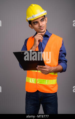 Jeune Indien homme travailleur de la construction à l'arrière-plan gris Banque D'Images