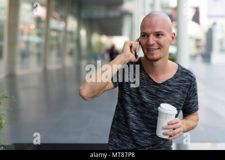 Young heureux homme chauve beach café papier Banque D'Images