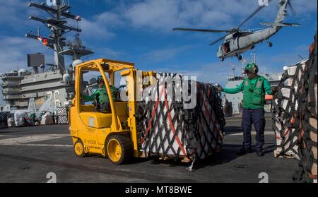 170715-N-OY799-301 CORAL SEA (15 juillet 2017) marins transporter des palettes sur le pont comme un MH-60S Sea Hawk, à partir de l 'île de la mer des Chevaliers d'hélicoptères de combat Squadron (HSC), offre 25 palettes de la commande de transport maritime de marchandises militaires et munitions ship USNS Charles Drew (T-AKE 10) à la marine de l'avant-déployé, porte-avions USS Ronald Reagan (CVN 76), dans le cadre d'un ravitaillement en mer au cours de Sabre 2017 Talisman. Talisman Sabre est un exercice difficile et réaliste qui rassemble les membres de plus près et améliore à la fois la capacité de l'Australie et des États-Unis, à titre bilatéral et multilater Banque D'Images