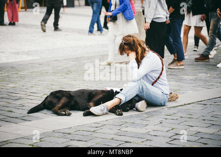 République tchèque, Prague, 25 juillet 2017 : une belle jeune femme peintre est assis sur le sol au milieu de la place et nulles, à côté d'elle se trouve un blac Banque D'Images