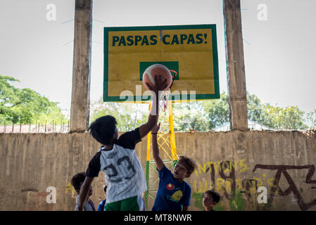 Les enfants de la communauté locale de jouer au basket-ball dans les jeux où entre les Marines américains affectés au 9e Bataillon d'appui du génie de jouer contre des soldats de l'Armée Philippine affecté à la 522ème bataillon de génie et de construction au cours d'un jeu de pick-up à l'école élémentaire en Calangitan Capas, Tarlac, Philippines, le 16 mai 2018. Balikatan 2018, dans sa 34e version, est un américain annuel-exercice d'entraînement militaire des Philippines a porté sur une grande variété de missions, y compris l'assistance humanitaire et les secours en cas de catastrophe, le contre-terrorisme et autres opérations militaires conjointes qui s'est tenue du 7 au 18 mai. Banque D'Images