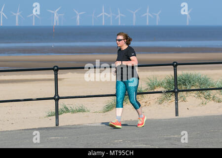 Femme en train de courir sur la promenade du front de mer à Crosby, Liverpool. Mai 2018. Météo au Royaume-Uni : journée d'été lumineuse sur la côte nord-ouest, les résidents et les vacanciers de la région s'exerceront tôt le matin sur le sentier côtier et la plage de Merseyside. La plage est ornée de litière Spring Bank Holiday avec des poubelles débordées et des ordures qui soufflent dans la brise. Les conteneurs du Conseil de Sefton sont manifestement inadéquats pour la quantité de déchets plastiques. Crédit : MediaWorldImages/AlamayyLiveNews. Banque D'Images