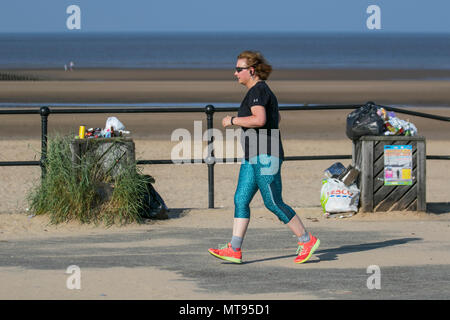 Femme en train de courir sur la promenade du front de mer à Crosby, Liverpool. Mai 2018. Météo au Royaume-Uni : journée d'été lumineuse sur la côte nord-ouest, les résidents et les vacanciers de la région s'exerceront tôt le matin sur le sentier côtier et la plage de Merseyside. La plage est ornée de litière Spring Bank Holiday avec des poubelles débordées et des ordures qui soufflent dans la brise. Les conteneurs du Conseil de Sefton sont manifestement inadéquats pour la quantité de déchets plastiques. Crédit : MediaWorldImages/AlamayyLiveNews. Banque D'Images