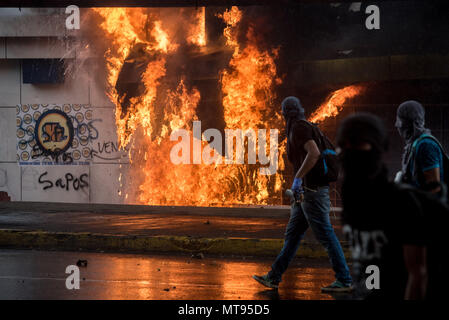 Managua, Nicaragua. 28 mai, 2018. 28.05.2018, le Nicaragua, Managua : un groupe de personnes à marcher le long de la façade flamboyante de l'état station de radio "Nueva Radio Ya". Les étudiants qui étaient barricadés autour de l'Université de génie distanciés de l'action. Jusqu'à présent, il n'est pas clair qui est responsable de l'action. Crédit : Carlos Herrera/dpa/Alamy Live News Banque D'Images