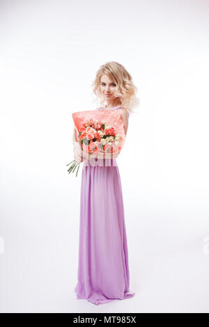 Portrait de femme avec de magnifiques cheveux bouclés blondy make-up parfait. Holding bouquet. Longue soirée robe violette Banque D'Images