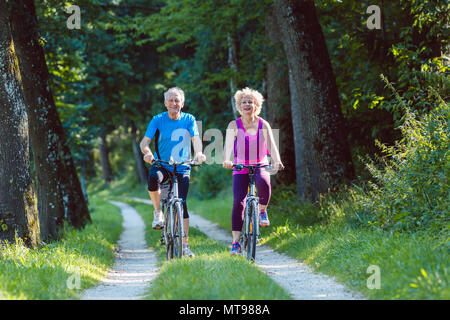 Heureuse et active senior couple riding bicycles en plein air dans le parc Banque D'Images